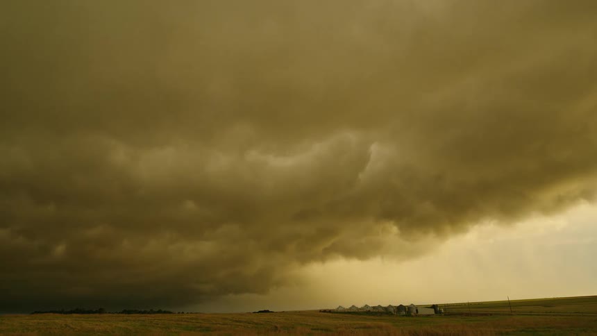 Time lapse of impossibly colored golden storm clouds as the storm lifts and then crashes down on the rural landscape in a dynamic and high energy way