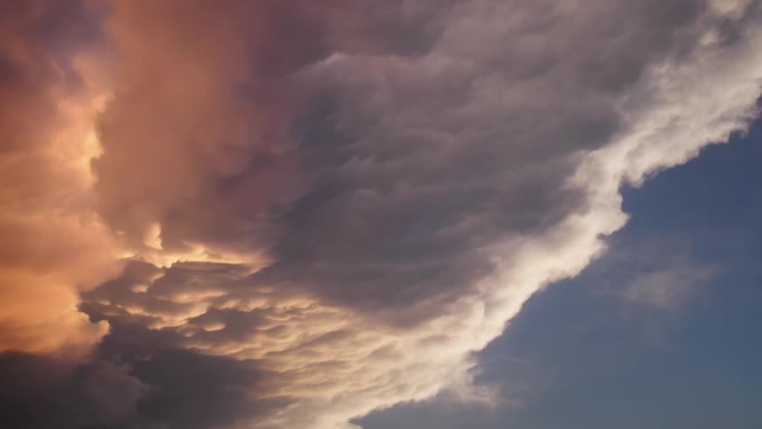 A magical and ethereal time lapse shot of a huge anvil cloud building and shifting during a pink, blue and golden hour sunset