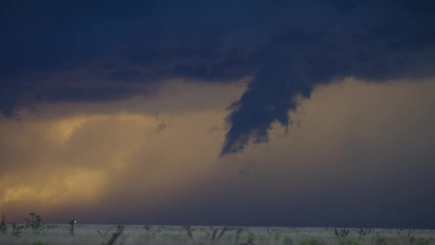 Tight shot time lapse of a spin up funnel cloud tornado forming then dissipating with lightning flashing and crashing at sunset in a severe thunderstorm