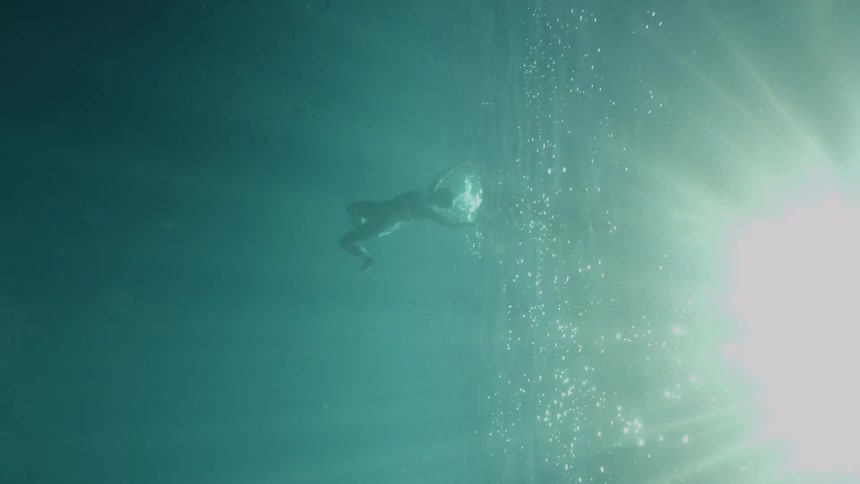 A person diving and swimming underwater in the ocean
