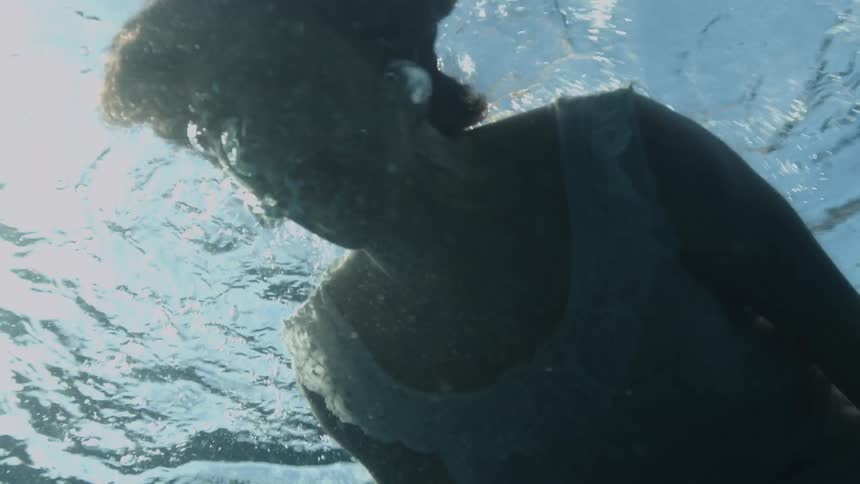 A woman in a dress screaming underwater