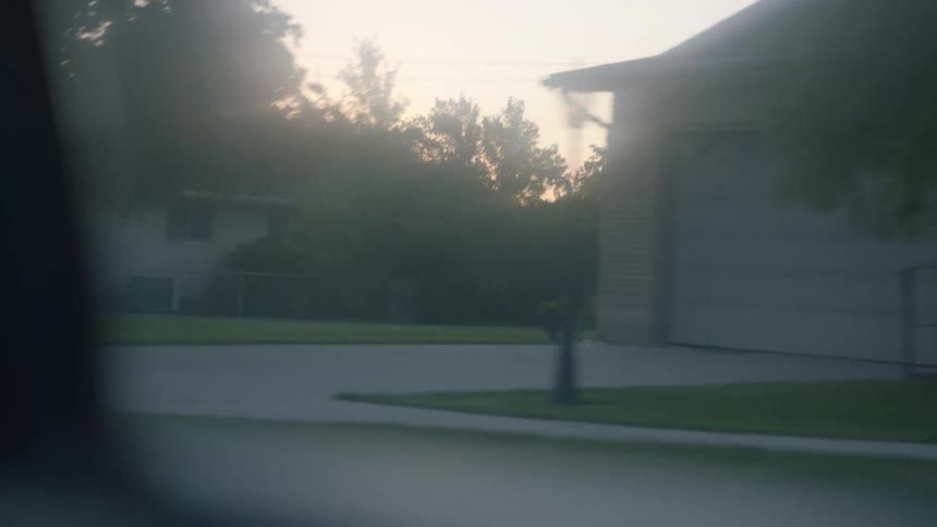 Vehicle drives down the street in the neighborhood at dusk