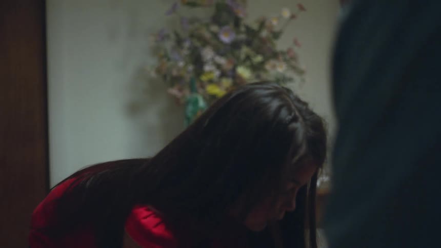 Little girl picks up a stuffed animal while an elderly man watches in a room with flowers behind them