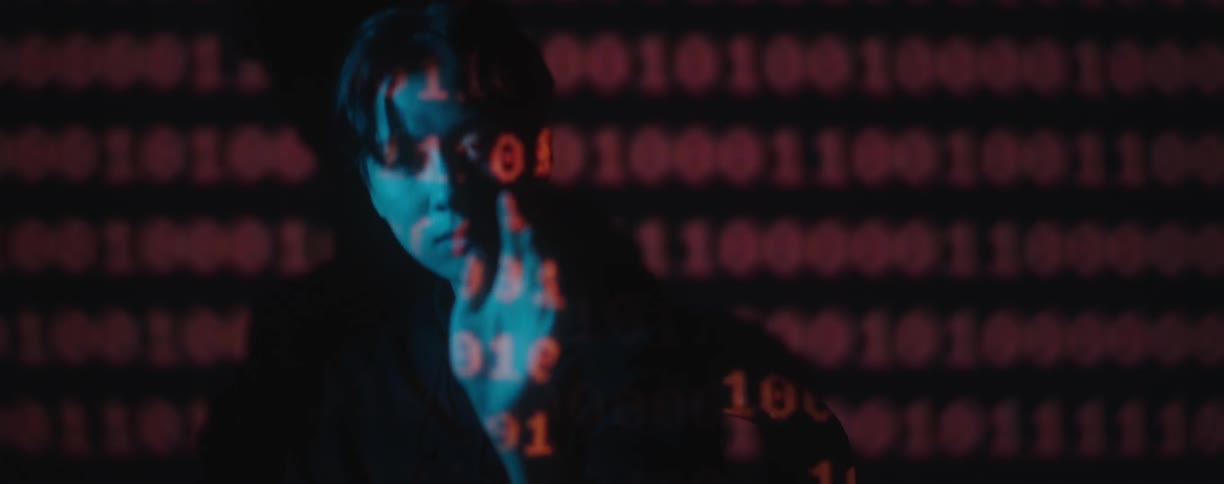 A woman holds out her hand in a dark room with red numbers projected onto her