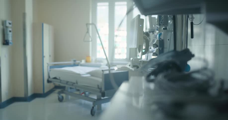 An empty hospital bed surrounded by medical equipment