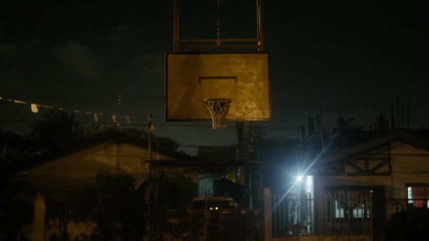 Lightning flashes in the night sky near a basketball hoop