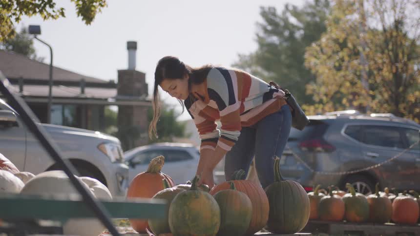 Woman with a sweater and jeans buys a pumpkin from pumpkin store