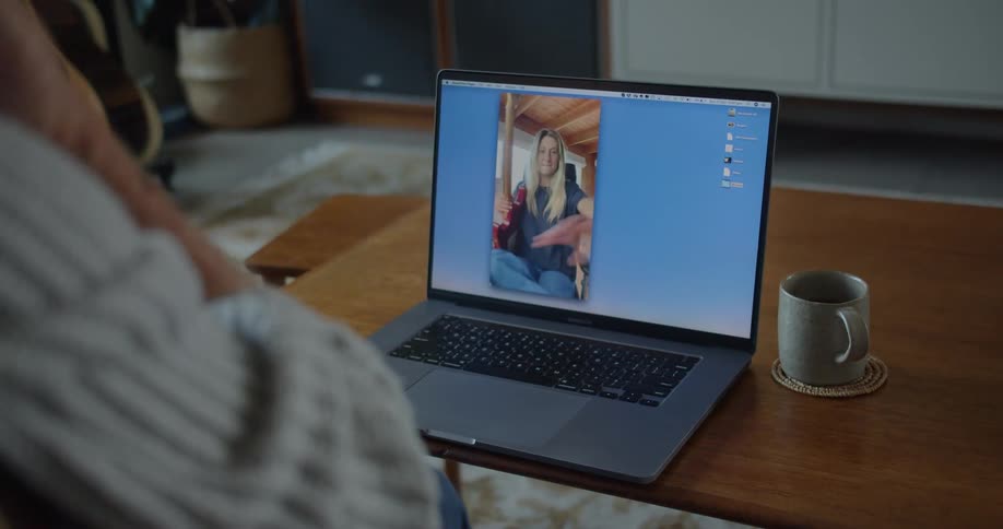 Two people wave at one another as they video chat on a laptop