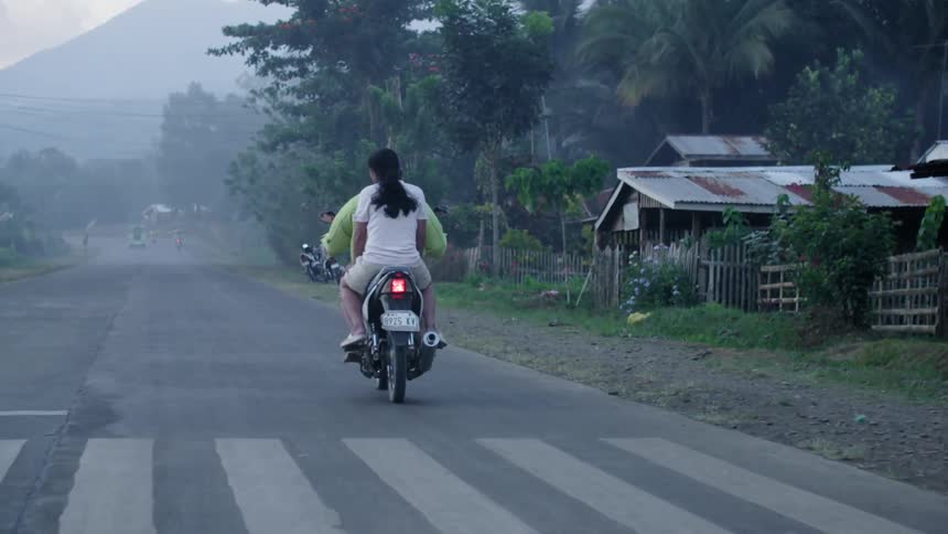 Two people are riding down a street on a motorcycle