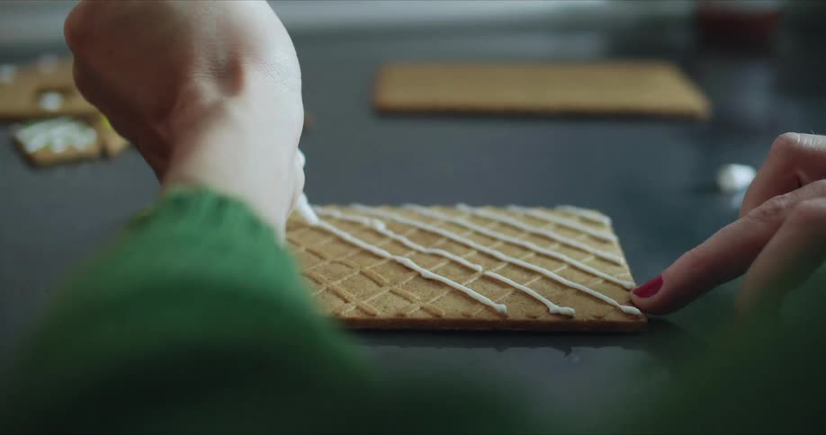 Woman glazing cookies over a tray at home