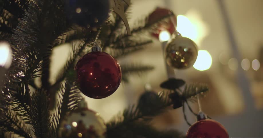 Red and silver round ornaments hang on a christmas tree