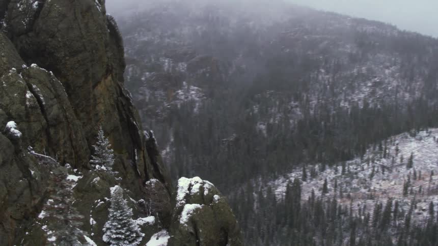 Aerial view of mountains with snow cliffs and cloudy overcast and snowy weather