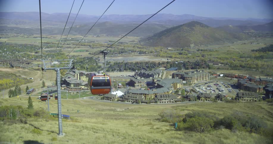 Riding in a car moving on a cable over a small town with mountains in background during the day