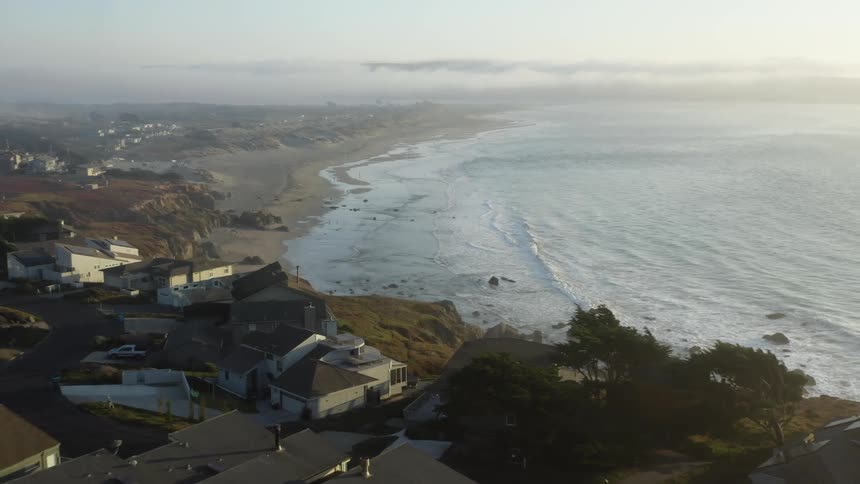 Aerial view from a drone of a neighborhood next to a beach by the ocean in daylight
