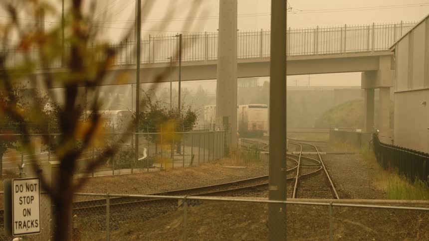 A subway drives over a overpass with a train parked underneath