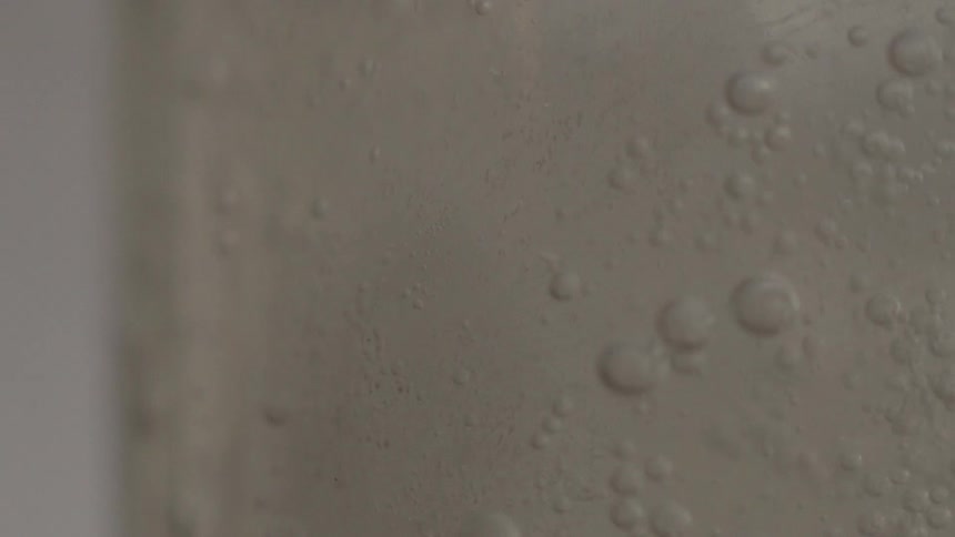 Clear liquid moving around in a clear container and making bubbles