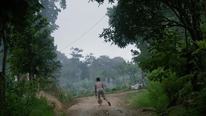 A boy is throwing around a ball as he moves down a trail