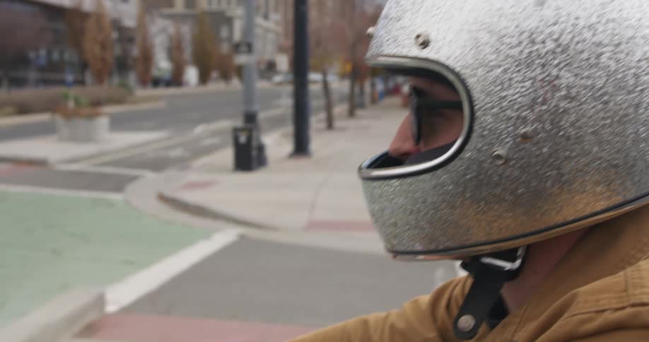A person wearing a sparkly helmet rides their motorcycle in the city