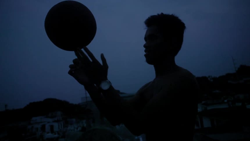 Man spins a basketball on his finger outside at night