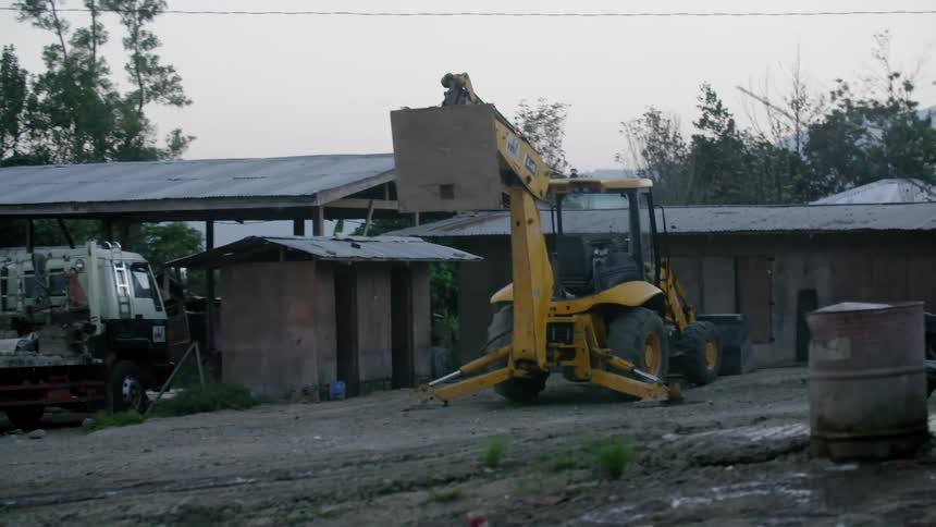 A piece of heavy equipment sitting in front of a small building