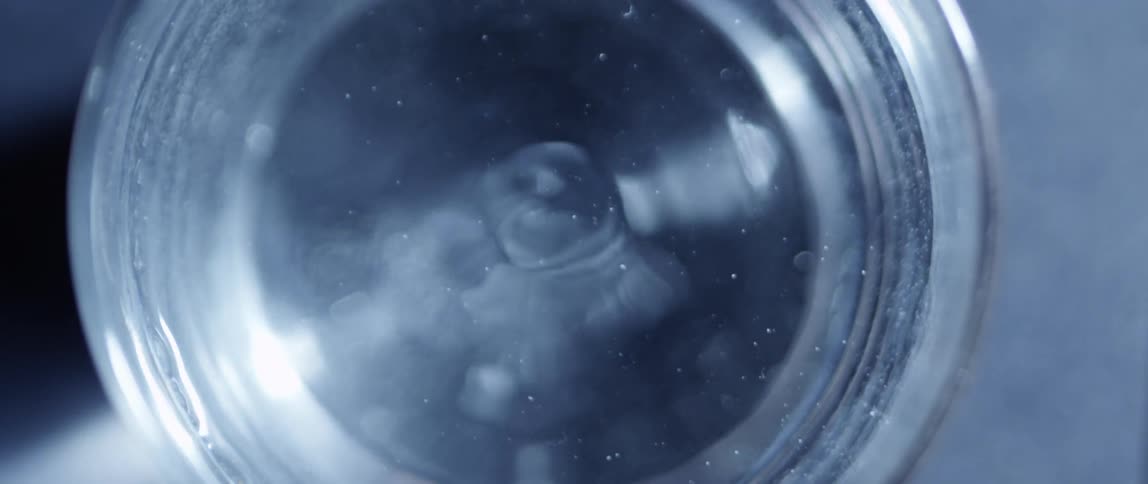 A glass of water is gently vibrating causing the contents to ripple and waver