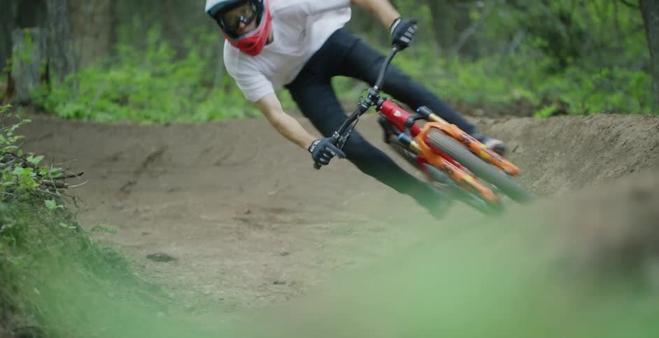Man riding a bike around a curve on a dirt path in the forest at daytime