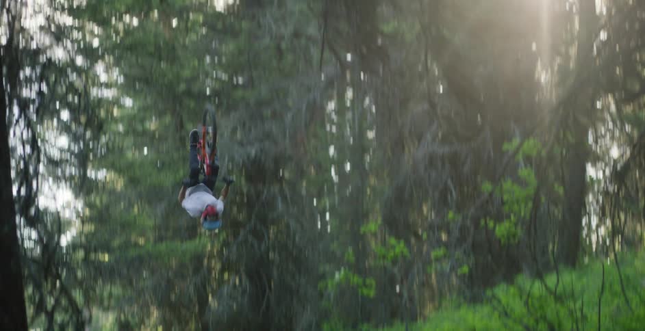 A man races his bicycle up the dirt hill and does a flip