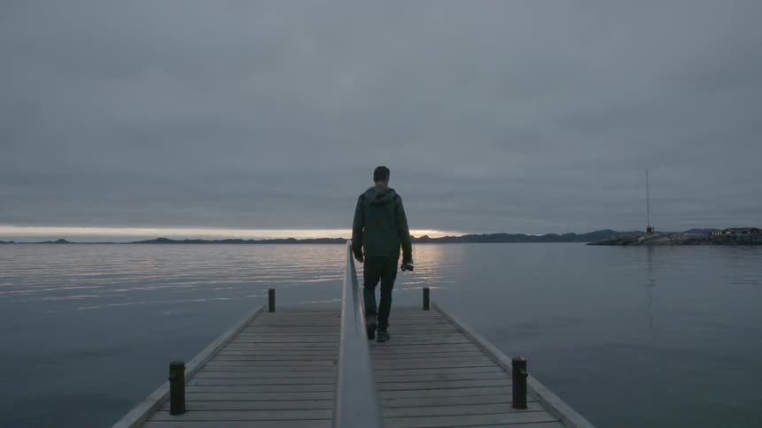 A man walking down a pier on a heavily overcast day