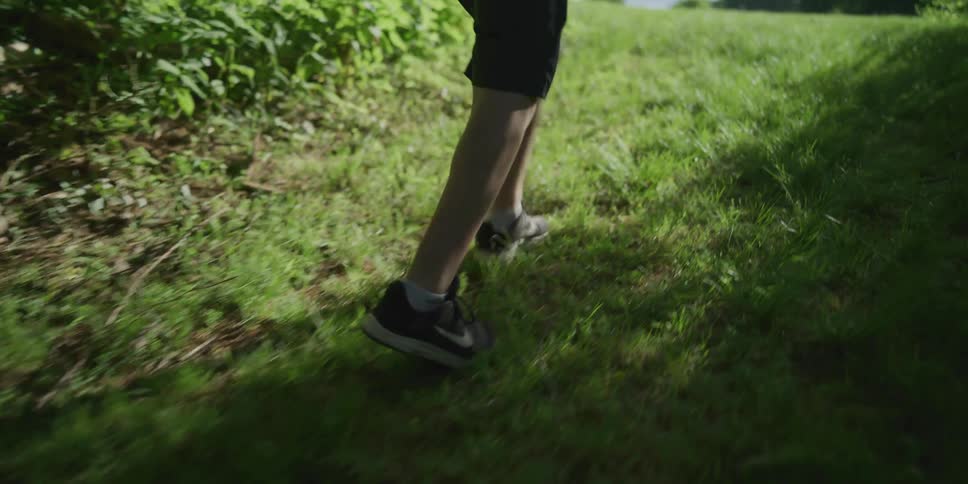 A young disabled boy walks through a public park