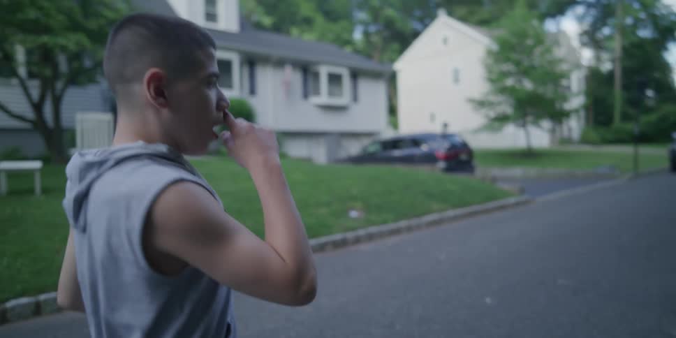A male teenager is walking for exercise down a residential street during the daytime