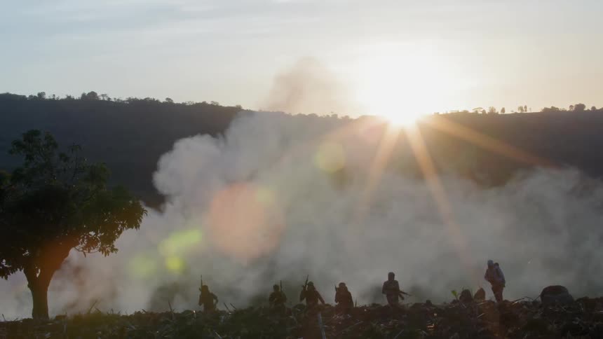 Soldiers are walking uphill on a smoke covered area