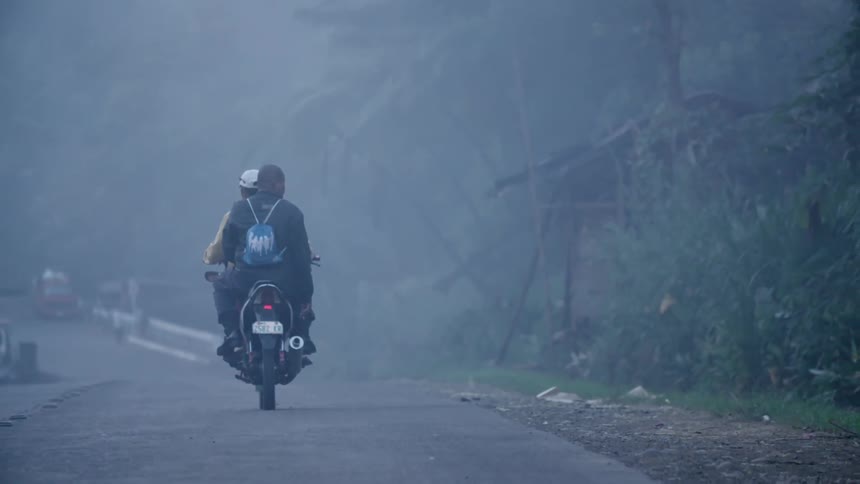 Two people riding one motorcycle down a road