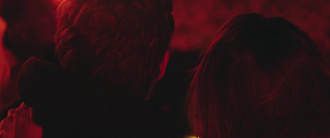Young couple sittingo outdoors under a red light recline leisurely into each others shoulders