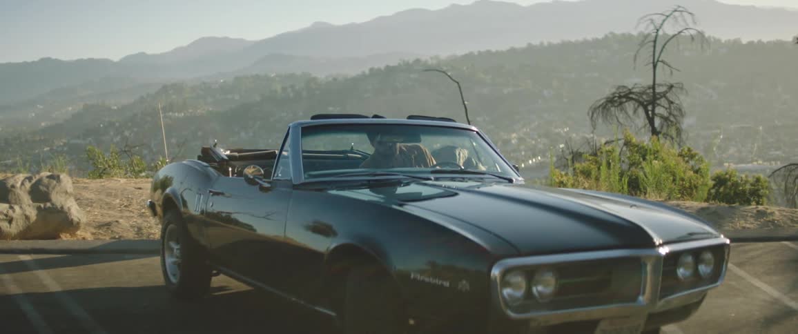 A man stands beside his vehicle looking at the mountain scenery then turns in gets inside