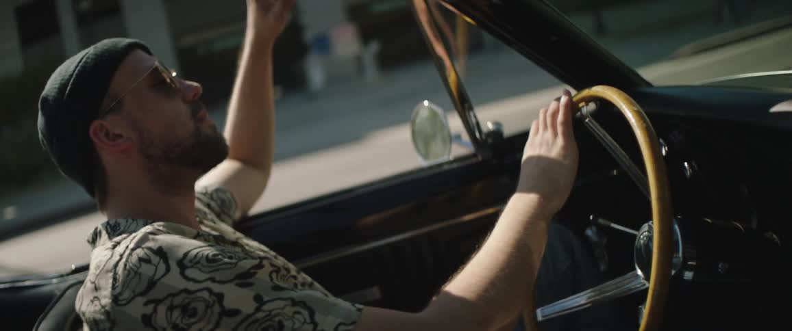 Man leisurely driving a convertible vintage car on the streets of a town