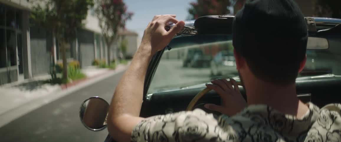 A man driving his convertible down a street