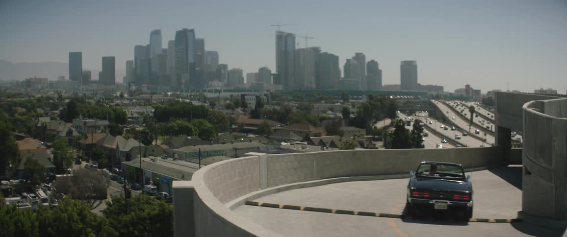 Convertible car driving down the ramp of a parking garage near the city skyline