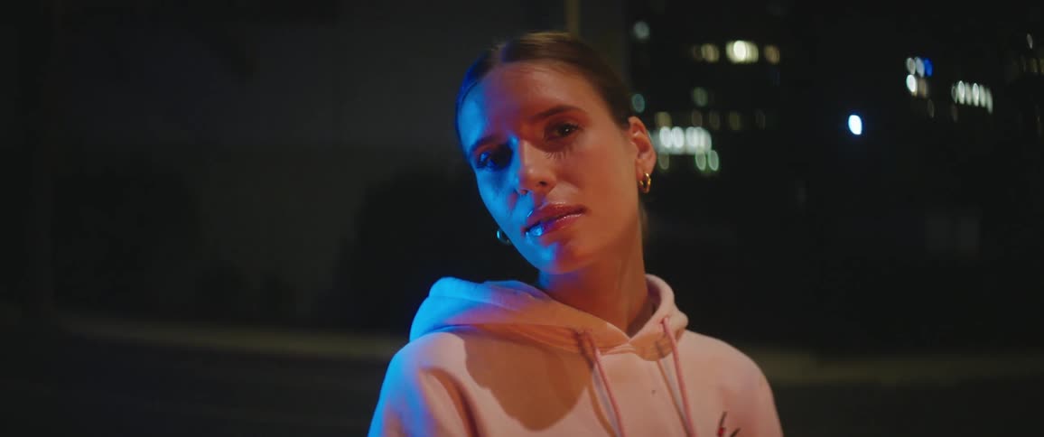 A young woman standing outside in the city at night