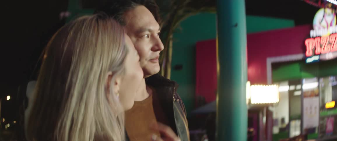 Young couple having fun dancing in the food court of an amusement park at night