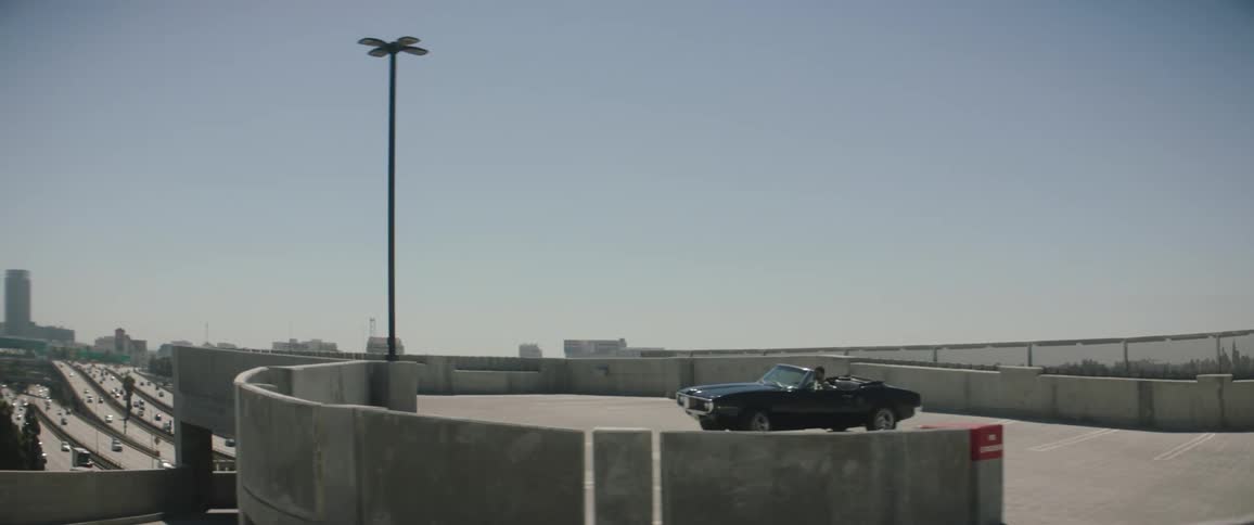 Car drives to the top of a parking garage in a large city