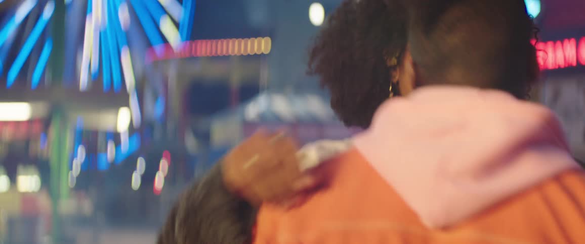 Young happy couple dancing on a colorful amusement park at night