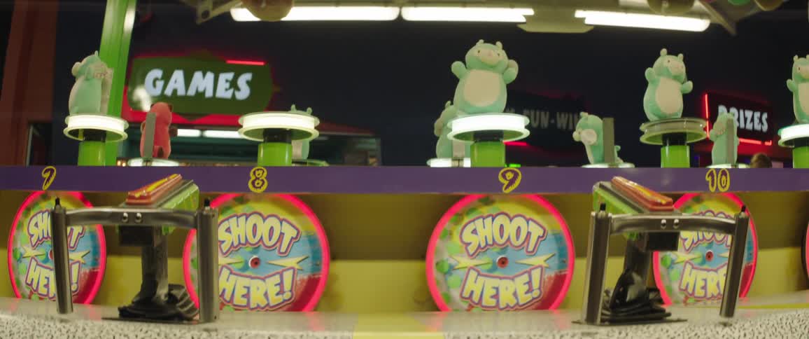 A carnival outdoors at night with a shooting game stand