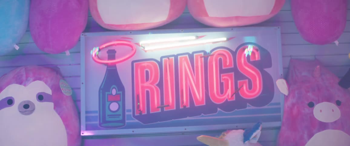Sign on the stall of an amusement park surrounded by plush toys