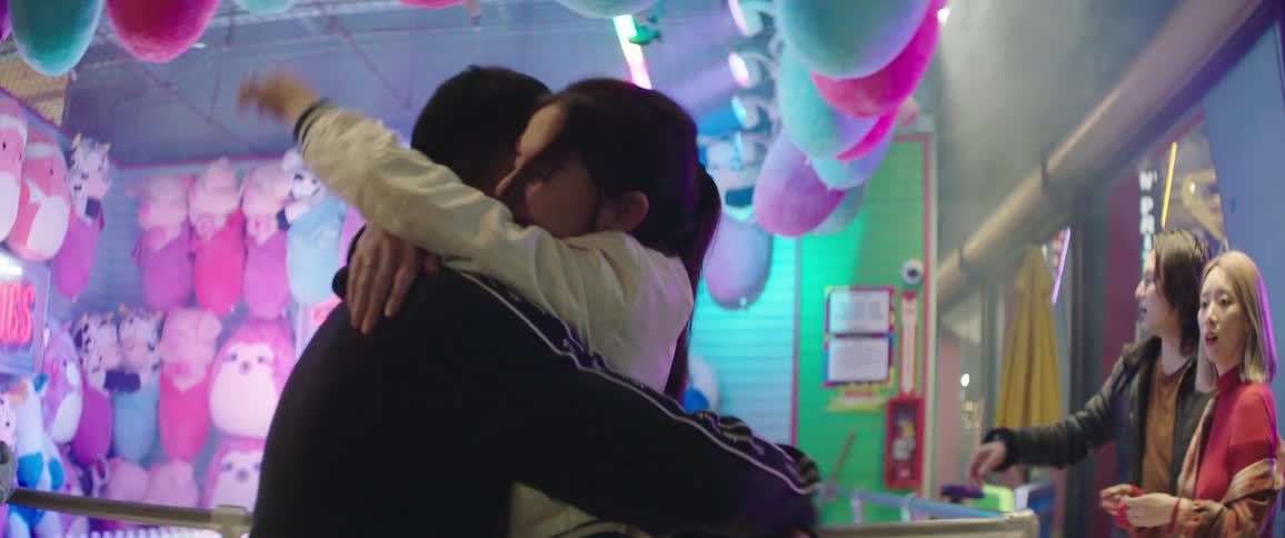 A young woman jumps up and down and hugs her boyfriend after winning a stuffed animal at a carnival