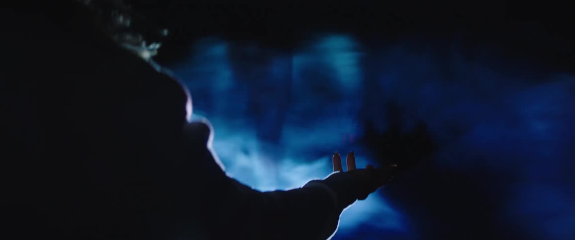 Smoke and bright lighting on a woman as she raises her hand