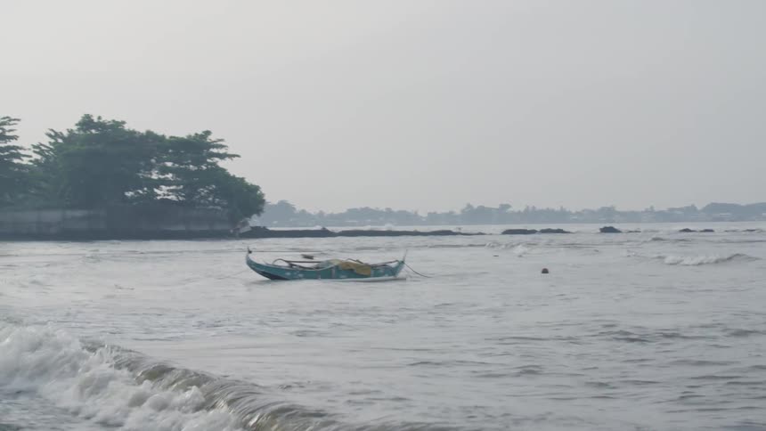 A boat is docked by the shore on a cloudy day