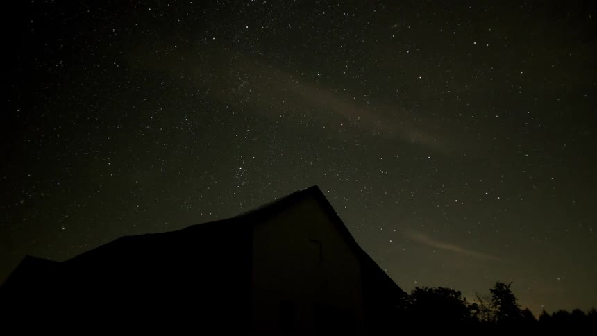 Time lapse of the stars in the night sky over a house in a rural area