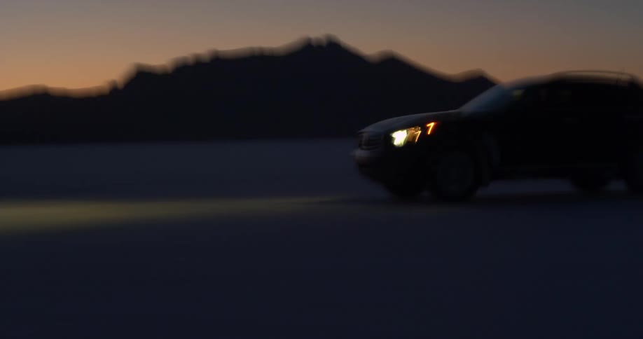 A car is driving on a road at dusk