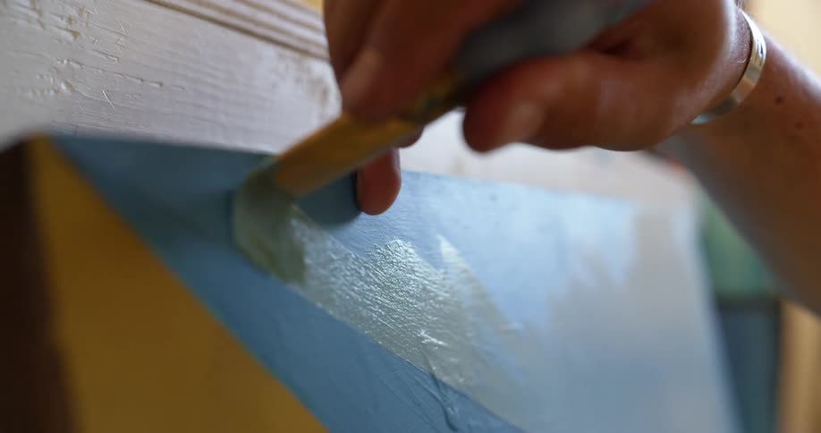 A person with a paintbrush painting on a canvas with paint
