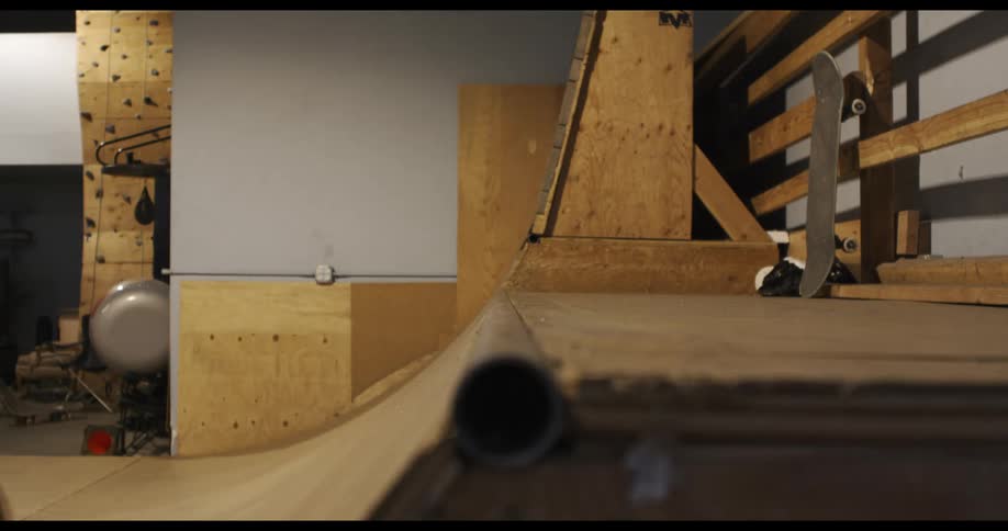 A skateboarder ascends a ramp and grinds along a pipe at the top before grinding back down